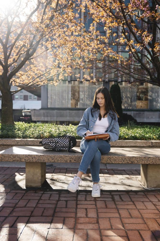 young woman studying on stone bench